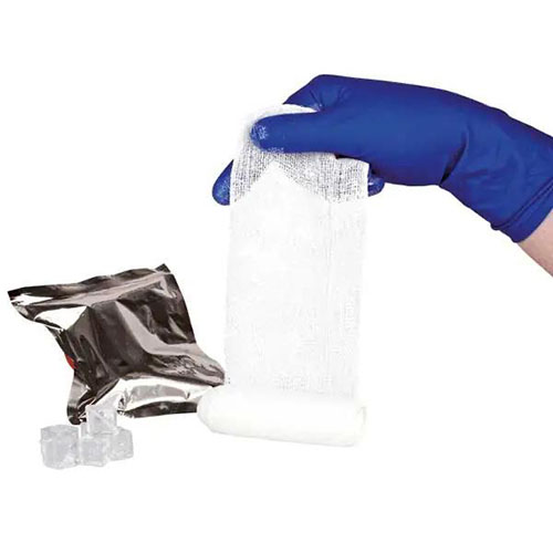 Eine elastische Zinkleimbinde die von einer Hand im blauen Handschuh langgezogen wird. Dhinter steht der Zink in einem Beutel.jpg